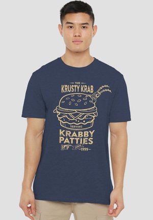 Navy blue short-sleeve t-shirt made of cotton features a gold graphic of a burger with text "Krusty Krab" and "Serving Krabby Patties since 1999."