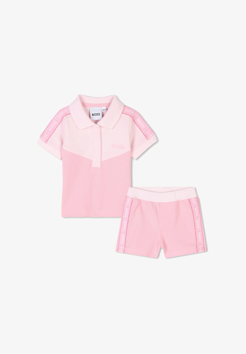 Polo rose à manches courtes avec un short assorti. Fabriqué en tissu doux, avec des rayures contrastées et un petit logo sur les deux pièces.