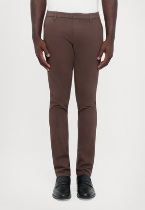 Brune slanke bukser laget av glatt stoff, med flat front, belteholder og sidelommer, kombinert med svarte sko.