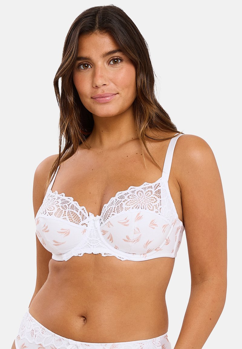 Soutien-gorge blanc avec des détails en dentelle et un motif floral. Dispose de bretelles ajustables et d'un fermoir à l'avant. Texture douce. Accents en dentelle assortis.