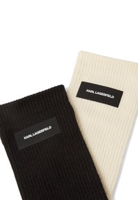 Skarpetki dziane w prążki w kolorze czarnym i kremowym. Każda z nich ma metkę z logo "KARL LAGERFELD" na mankiecie. Miękka tekstura, pionowe paski.
