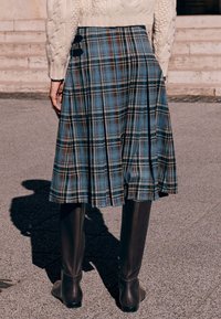 Plisowana spódnica do kolan w niebiesko-brązowy wzór tartanu, z bocznymi guzikami. Do tego dopasowane brązowe wysokie kozaki za kolano.
