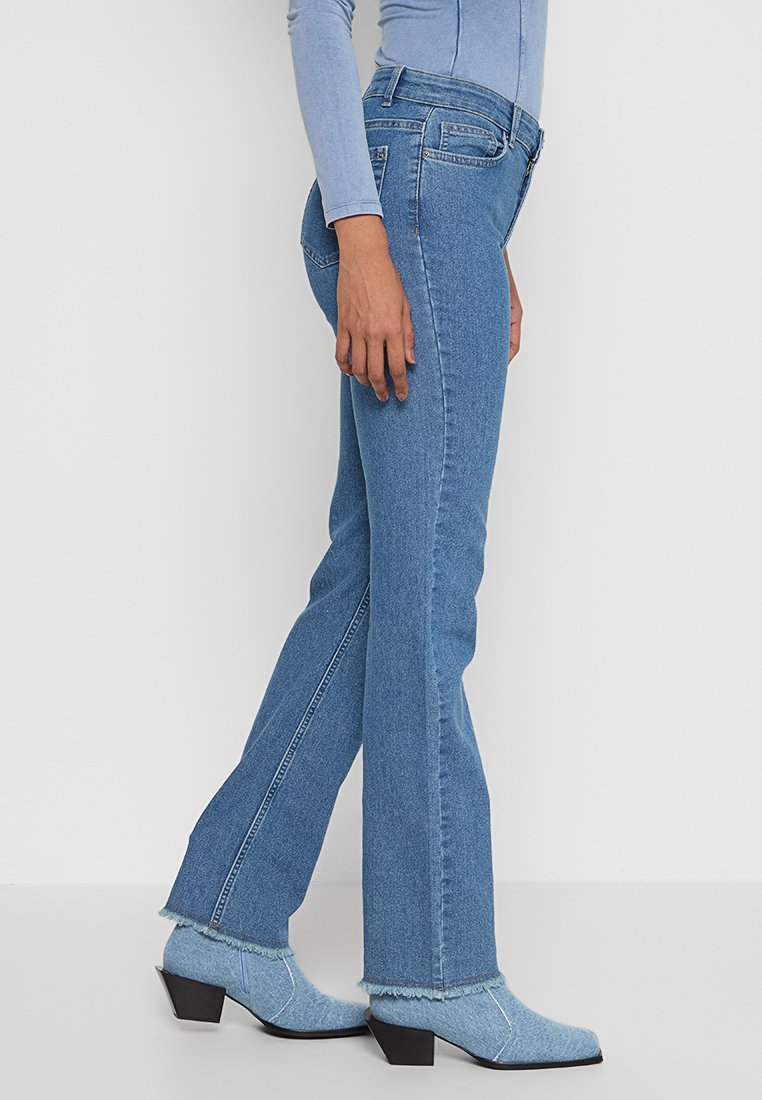 Blauwe denim jeans met een rechtvallend ontwerp, voorzien van een hoge taille, subtiele stiksels en rafelige zomen. Draag ze met bijpassende blauwe enkellaarsjes.