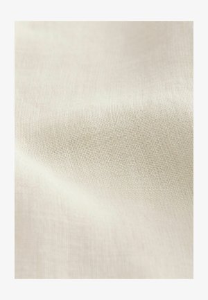 Tissu texturé beige clair avec un motif tissé, présentant des variations subtiles de couleur et de détail de surface. Texture douce et lisse dans l'ensemble.