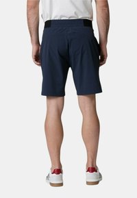 Pantaloni corti blu navy con vita elasticizzata, tasca laterale e una texture morbida e leggera. La lunghezza arriva a metà coscia, design semplice.