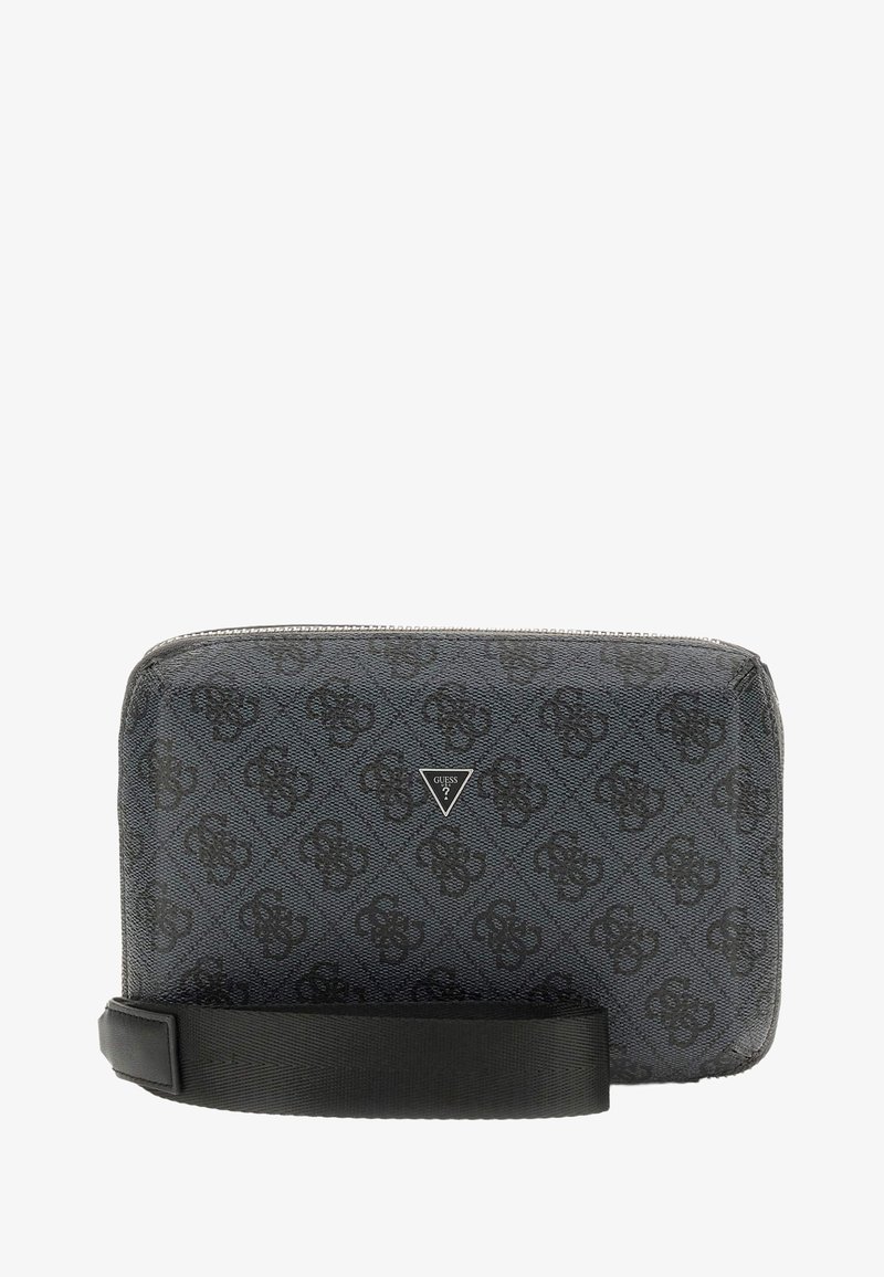 Petit porte-poignet noir Guess avec imprimé logo à motifs, plaque de logo en métal triangulaire et bracelet amovible sur fond blanc.