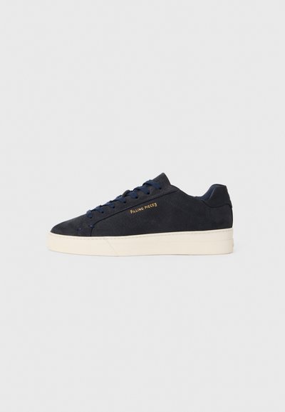 Mørkeblå ruskinds lavtop sneaker med hvid sål, mørkeblå snørebånd og "Filling Pieces" logo i guld på siden.