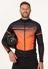 Svart och orange cykeltröja med ett geometriskt mönster, dragkedjestängning och långa ärmar. Tyget verkar slätt och elastiskt.