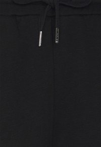 Svarta joggerbyxor i mjukt tyg, med ett dragsko i midjan med metalldetaljer och en texturerad yta.