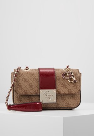 Braune Schultertasche mit Muster, rotem Lederriemen, goldener Kette sowie goldenem Logo-Emblem und Anhängern auf weißer Oberfläche.