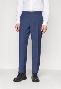 Dunkelblaue, maßgeschneiderte Hosen aus strukturiertem Stoff, mit flachem Bund, Gürtelschlaufen und schmaler Passform, kombiniert mit schwarzen Schuhen.