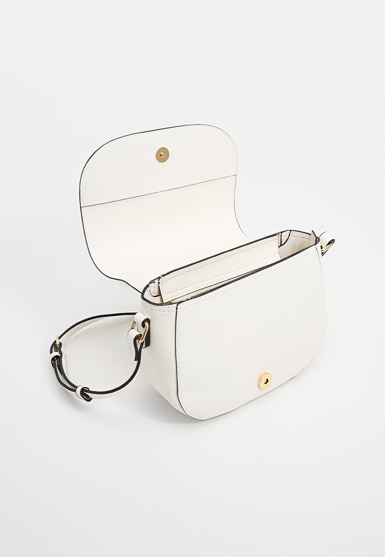 Sac en cuir blanc à bandoulière avec une forme incurvée, fermeture à bouton en métal doré et couture accentuée en noir. Intérieur ouvert sans compartiments.