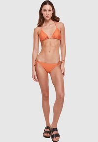 Twee-delig bikini in oranje, met een driehoekige top en verstelbare zijsluiting. Gladde textuur met een ontwerp dat minimale bedekking biedt.