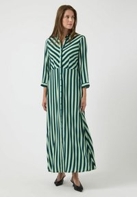 Zelené a světle zelené šaty s vertikálními proužky, límečkem, zapínáním na knoflíky vpředu a tříčtvrtečními rukávy. Mají volnější střih.