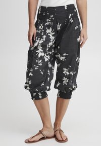 Czarne krótkie spodnie z lekkiego materiału w biały kwiatowy wzór, z elastycznym pasem i marszczonymi mankietami.