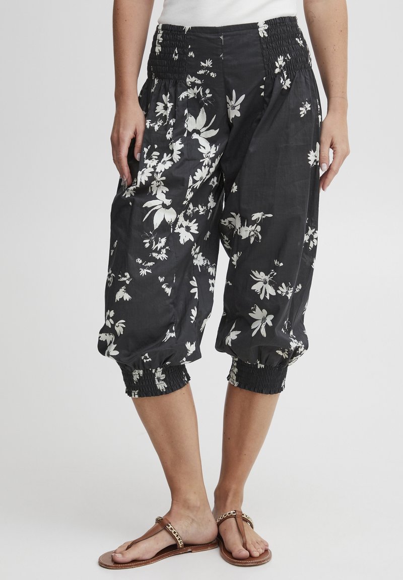 Czarne krótkie spodnie z lekkiego materiału w biały kwiatowy wzór, z elastycznym pasem i marszczonymi mankietami.
