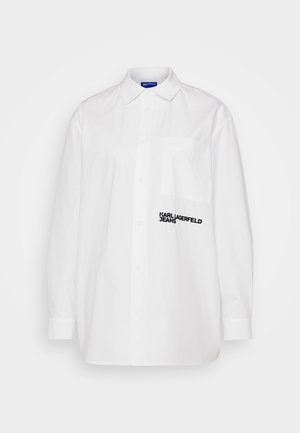 Valge nööbiga särk kraega, millel on tasku ja must "KARL LAGERFELD JEANS" tekstilogo vasakul rinnal. Sile tekstuur.