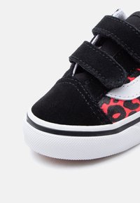 Μαύρο παιδικό αθλητικό παπούτσι με λευκή σόλα, μαύρες λουρίδες βέλκρο, λευκή πλευρική ρίγα και κόκκινο ύφασμα με λεοπάρ μοτίβο.