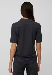 Ciemnoszara koszulka polo z krótkimi rękawami, gładka w dotyku, z klasycznym kołnierzykiem. Widok z tyłu pokazuje prosty design bez ozdób.