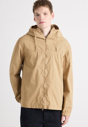 Tan hooded jacket with a front zipper, elastic cuffs, and a lightweight, textured fabric. Features drawstrings at the hood and simple design.