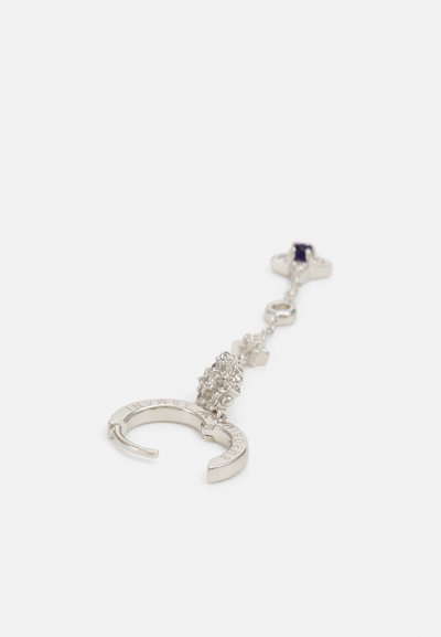 Silver earring with a curved design, featuring a cluster of clear stones and a dark purple accent at the top. Text engraved on the surface.
