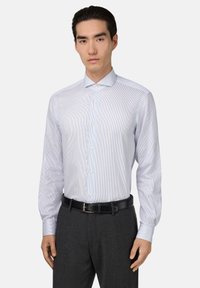 Camisa blanca de vestir con rayas verticales azules, cuello puntiagudo y mangas largas. Se lleva con pantalones grises y un cinturón negro.