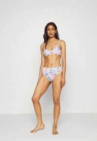 Conjunto de biquíni floral com fundo rosa e padrões tropicais em azul e verde; o top tem alças finas e design em v.