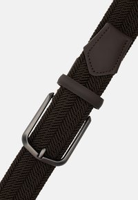 Hnědý pletený elastický pásek s černou kovovou přezkou a koženými detaily, zdobený vzorem rybí kosti. Robustní a flexibilní design.