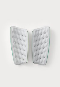 Witte schuimkussens met een gestructureerd oppervlak, voorzien van kleine gaatjes voor ventilatie, omrand door een dunne groene rand, gevormd voor ergonomische ondersteuning.