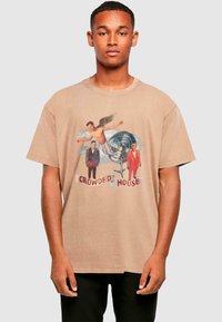 Beige bomulds t-shirt med grafisk tryk med figurer og teksten "CROWDED HOUSE." Kortærmet og afslappet pasform, minimal tekstur.
