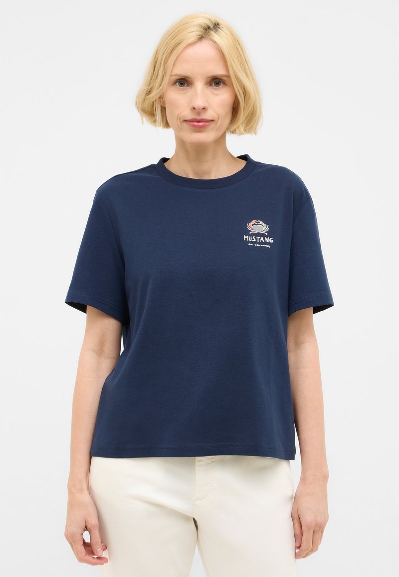 T-shirt en coton bleu marine à manches courtes, col rond, avec un motif de crabe brodé sur le devant et le texte « MUSTANG ». Coupe simple et décontractée.
