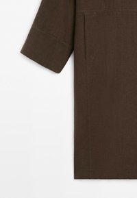 Brown long-sleeve garment with straight cut sleeve and minimalist design, shown from midsection to cuff on a white background.