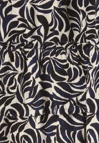 Tissu à motifs floraux comportant des feuilles bleu marine et noires sur un fond blanc, avec une surface texturée et un détail de taille froncée.