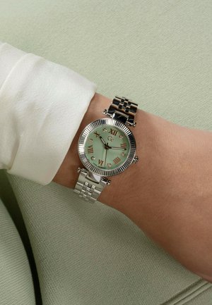 Silberner Edelstahl-Armbanduhr mit einem mintgrünen Ziffernblatt, römischen Ziffern und Edelsteinakzenten. Das Armband hat ein verlinktes Design.