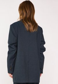 Blazer a righe blu scuro in tessuto testurizzato, caratterizzato da una vestibilità comoda, ampi rever e dettagli con bottoni sui polsini.