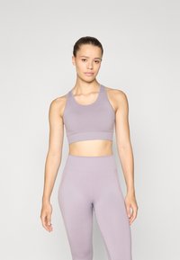 Haut de sport court lilas clair avec une bande côtelée, associé à un legging taille haute assorti. Texture douce et design ajusté.