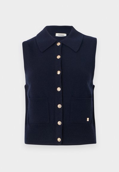 Ναυτικό μπλε πλεκτό αμάνικο πουλόβερ με κλασικό γιακά, χρυσά κουμπιά και δύο μπροστινές τσέπες. Χρυσή λεπτομέρεια λογότυπου στο πλάι.