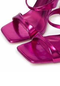 Sandalias de tacón metálicas fucsias con punta cuadrada, que presentan dos correas finas sobre el pie y un acabado elegante.