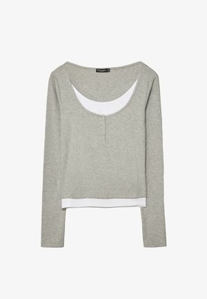 Hellgraues Langarm-Oberteil mit Lagenoptik, weißem inneren Ausschnitt und Saumdetaillen, mit einem Rundhalsausschnitt und drei kleinen Knöpfen auf der Vorderseite.