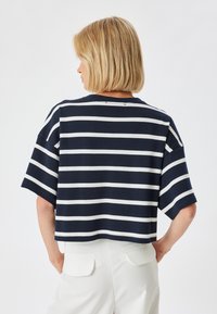 Top cortado de rayas en azul marino y blanco con mangas cortas y cuello redondo. Tejido de punto con una textura suave, que presenta un ajuste holgado.
