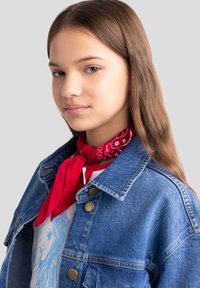 Punane bandana sall valge paisley mustriga, seotud kaela ümber, koos sinise teksajaketiga, millel on kuldsed nööbid.