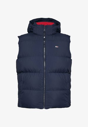 Námorníckomodrý vyp puffa s vysokým golierom, predným zipsom, dvomi bočnými vreckami a červenou podšívkou; na hrudi sa nachádza malé logo.