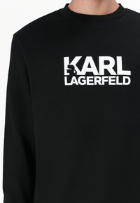 Schwarzes Sweatshirt aus Baumwolle mit einem weißen grafischen Logo-Text "KARL LAGERFELD" und einem Silhouetten-Design auf der Brust.