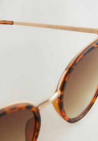 Schildpatt-Sonnenbrille mit verlaufenden braunen Gläsern, goldenen Metallakzenten an den Bügeln und "MADE IN CHINA DG0924" eingraviert.