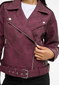 Burgundiapunane kunstnahast mootorratturite jakk hõbedaste tõmblukkude, laiade kraede, küljetaskute ja vööga taljemahuga ning siledapinnalise tekstuuriga.