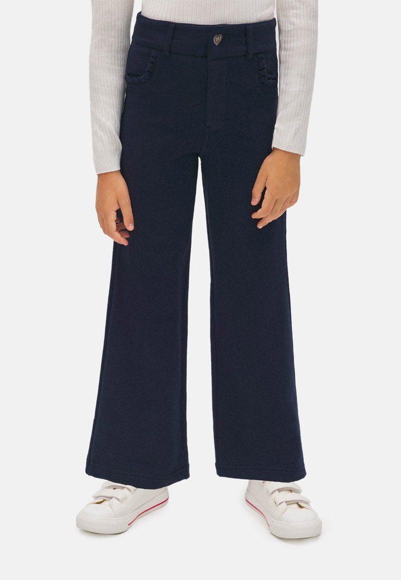 Pantalones de pierna ancha en azul marino, fabricados en algodón, que cuentan con dos bolsillos frontales, una cinturilla de altura media y un pequeño emblema decorativo en la cintura.