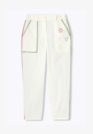 Pantalon blanc avec de grandes poches avant bordées de coutures vertes et rouges, avec broderies de soleil, cœur et quadrillage sur la poche droite.