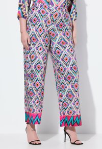 Färgglada mönstrade vida byxor har en geometrisk design i rosa, blå och gyllene toner, med en enfärgad rosa kant nertill.