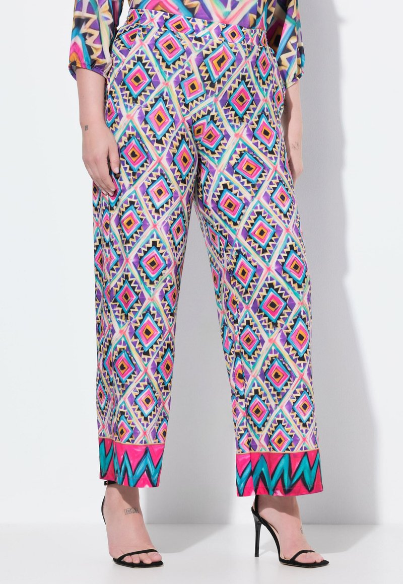 Färgglada mönstrade vida byxor har en geometrisk design i rosa, blå och gyllene toner, med en enfärgad rosa kant nertill.