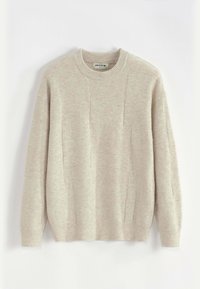 Pull en tricot beige clair avec un col rond, des épaules tombantes et des poignets côtelés. Présente un motif texturé subtil sur l'ensemble.